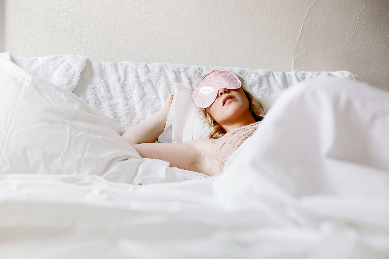 Woman sleeping with eye mask with white sheets